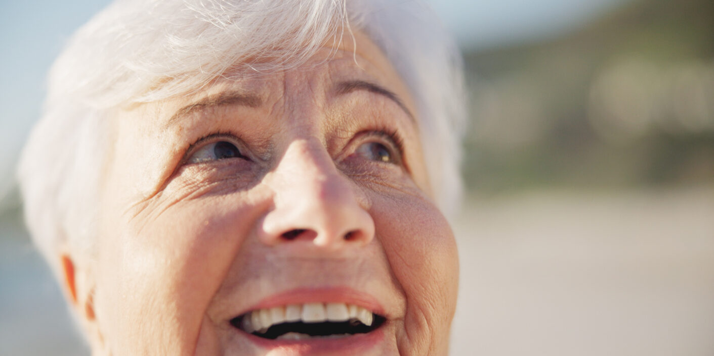 Sunset, smile and senior woman at a beach with peace outdoor in nature, sea and elderly female person with mindfulness. Relax, happy and calm old lady thinking by the ocean on holiday in retirement